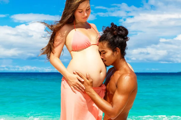 Glückliches und junges schwangeres Paar, das Spaß an einem tropischen Strand hat. — Stockfoto