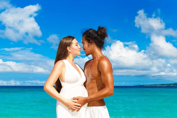 Glad och unga gravida par att ha kul på en tropisk strand. — Stockfoto