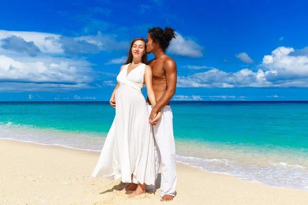Glad och unga gravida par att ha kul på en tropisk strand. — Stockfoto