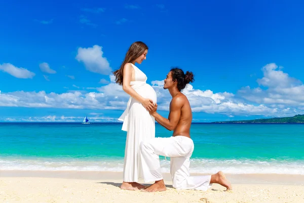 Gelukkig en jonge zwangere paar plezier op een tropisch strand. — Stockfoto