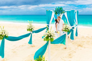 Mavi bir tropik sahilde düğün töreni. Mutlu damat ve br