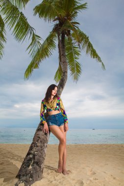 Genç güzel kadın rahatlatıcı bir tropikal palmiye ağacının altında