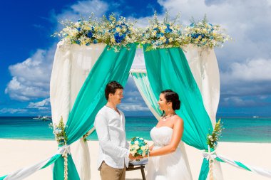 Mavi bir tropik sahilde düğün töreni. Mutlu damat ve br