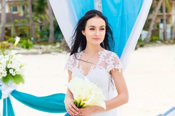Ślub na tropikalnej plaży w kolorze niebieskim. Szczęśliwa panna młoda pod — Zdjęcie stockowe