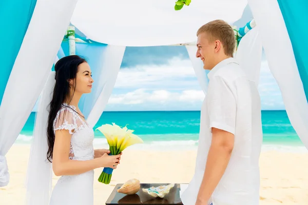 De ceremonie van het huwelijk op een tropisch strand in blauw. Gelukkige bruidegom en br — Stockfoto
