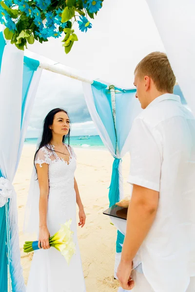 De ceremonie van het huwelijk op een tropisch strand in blauw. Gelukkige bruidegom en br — Stockfoto