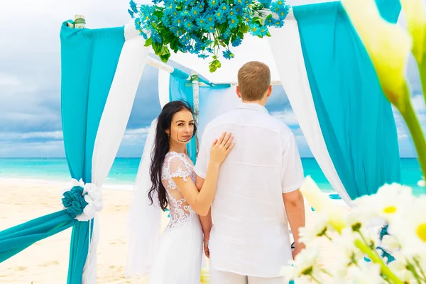 De ceremonie van het huwelijk op een tropisch strand in blauw. Gelukkige bruidegom en br — Stockfoto