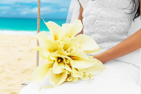 Ramo de boda acostado en el regazo de la novia en una playa tropical — Foto de Stock