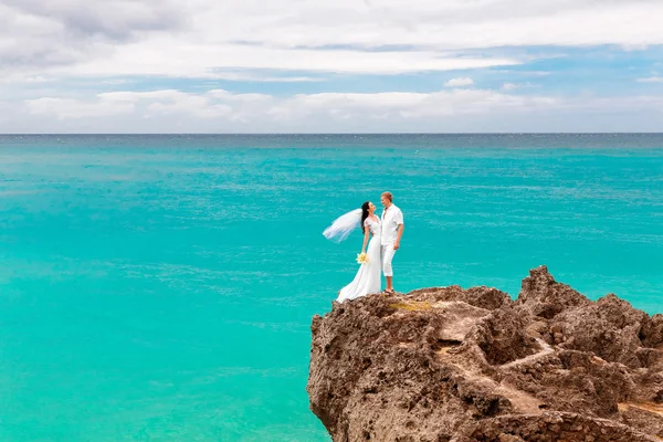 Šťastný ženich a nevěsta na skále. Tyrkysové moře v poz — Stock fotografie