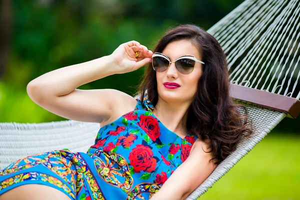 Junge Frau mit Sonnenbrille und langen dunklen Haaren entspannt in der Hängematte — Stockfoto