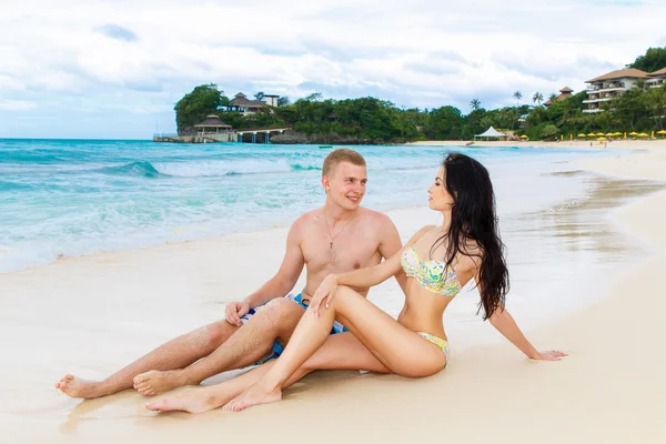 Jovem casal feliz amoroso na praia tropical, sentado na areia — Fotografia de Stock