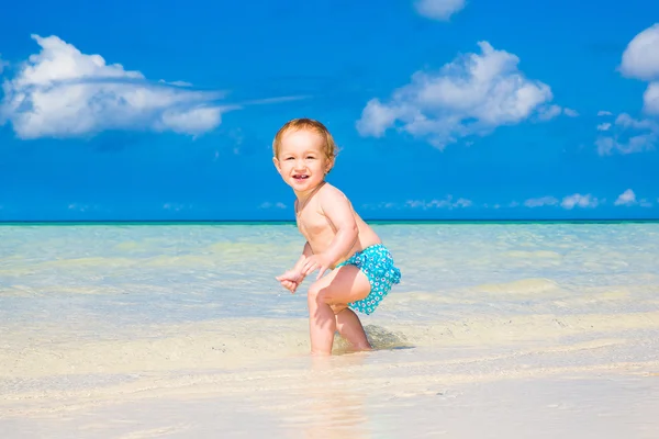 Ett litet barn ha roligt på en tropisk strand. — Stockfoto