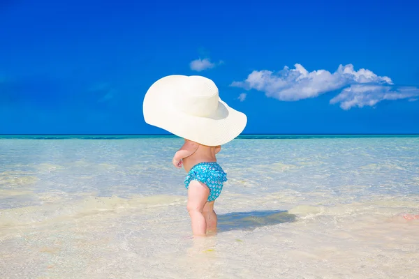 Uma criança pequena com um grande chapéu de palha branco se divertindo em um tropical — Fotografia de Stock