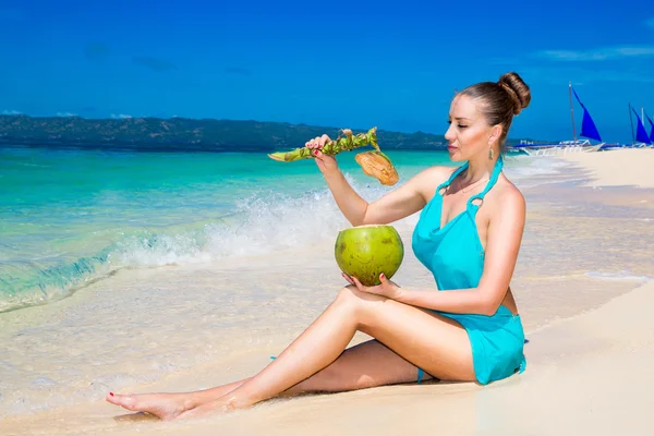 Young beautiful girl in blue dress, drinking coconut water on tr — Stock Photo, Image