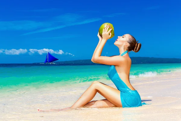 Young beautiful woman in blue dress, drinking coconut water on t — Stock Photo, Image