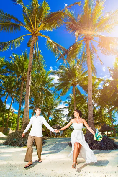 Happy bride and groom having fun on a tropical beach under the p — Stock Photo, Image