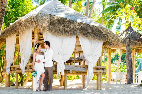 Happy bride and groom having fun on a tropical beach under the p — Stock Photo, Image