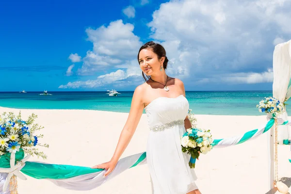 De ceremonie van het huwelijk op een tropisch strand in blauw. Gelukkige bruid onder — Stockfoto