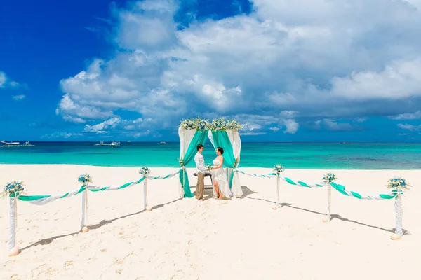 De ceremonie van het huwelijk op een tropisch strand in blauw. Gelukkige bruidegom en br — Stockfoto