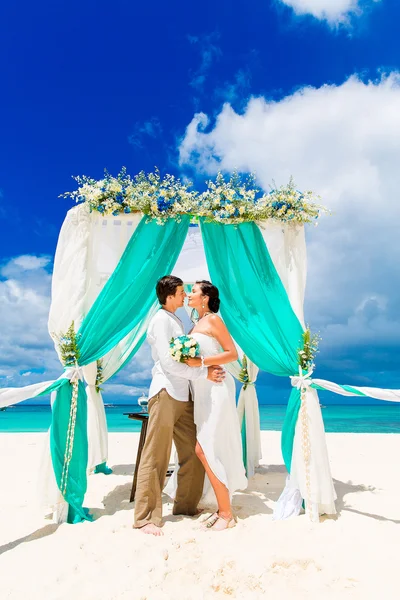 De ceremonie van het huwelijk op een tropisch strand in blauw. Gelukkige bruidegom en br — Stockfoto
