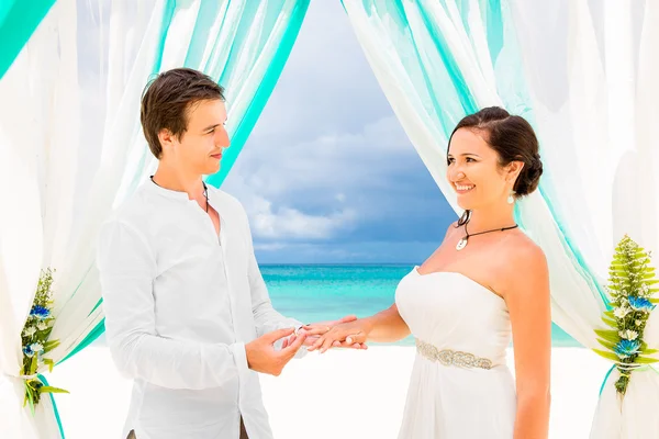 Bruidegom een verlovingsring te geven aan zijn bruid onder de boog deco — Stockfoto