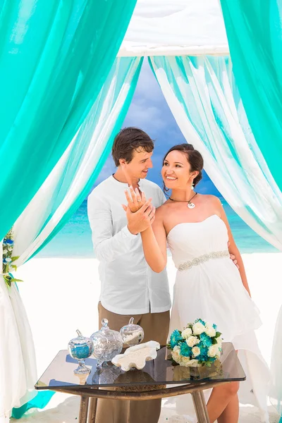 De ceremonie van het huwelijk op een tropisch strand in blauw. Gelukkige bruidegom en br — Stockfoto