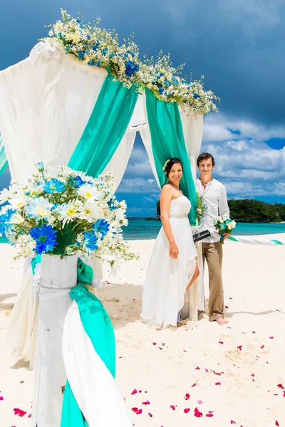Az esküvői szertartás egy trópusi tengerparton kék. Boldog vőlegény és br — Stock Fotó