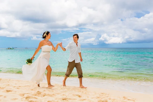 Happy brudgummen och bruden att ha kul på den tropiska stranden. Vi — Stockfoto