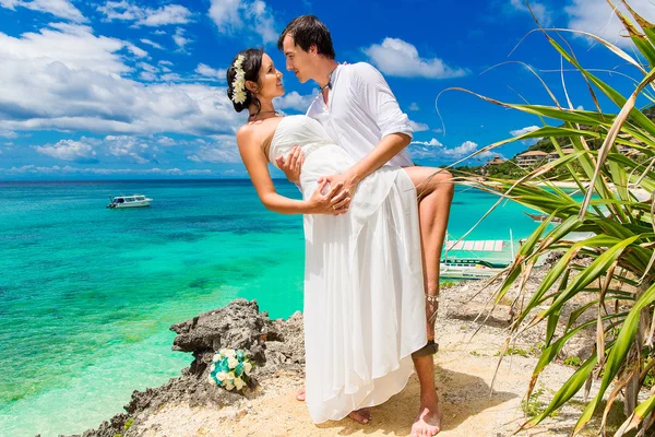 Happy bride and groom having fun on a tropical beach under the p — Stock Photo, Image