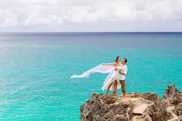 Feliz novio y novia en la roca. Mar turquesa en el backgrou —  Fotos de Stock