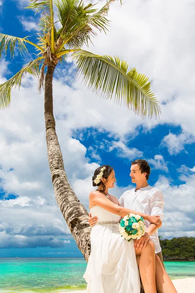 Happy groom and bride having fun on the sandy tropical beach und — Stock Photo, Image