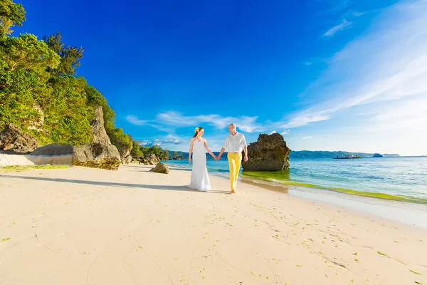 Bride and groom on a tropical beach with the sunset in the backg — Stock Photo, Image