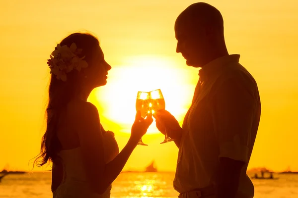 Silhouette di coppia che si gode un bicchiere di champagne sul bea tropicale — Foto Stock