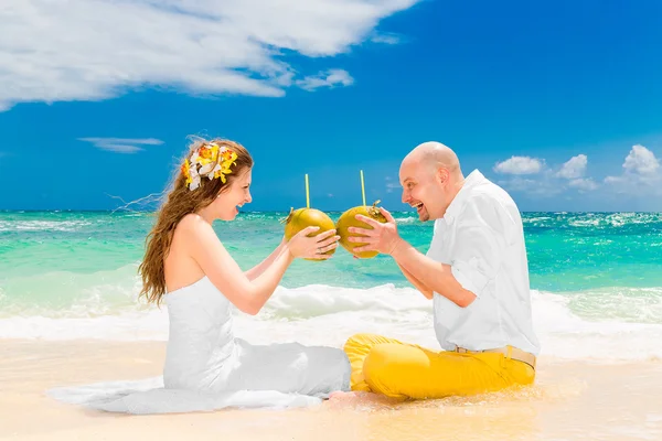 Gelukkige bruid en bruidegom drinken kokosnoot water en plezier op een tr — Stockfoto