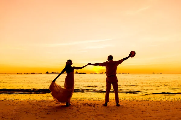 Bride and groom on a tropical beach with the sunset in the backg — Stock Photo, Image