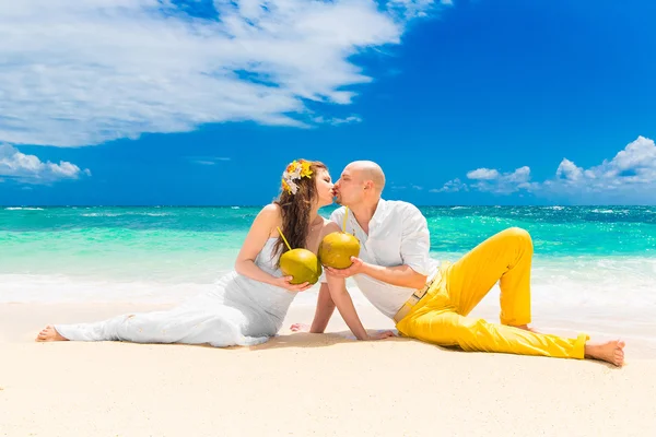 Glückliche Braut und Bräutigam trinken Kokoswasser und haben Spaß auf einem tr — Stockfoto