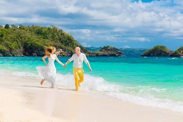 Happy bride and groom having fun on a tropical beach — Stock Photo, Image