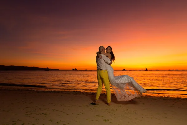 Braut und Bräutigam amüsieren sich an einem tropischen Strand bei Sonnenuntergang — Stockfoto