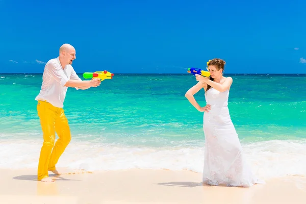 Novia feliz y novio divirtiéndose en las olas en una playa tropical. Boda y luna de miel en la isla tropical . — Foto de Stock