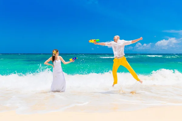 Lyckliga bruden och brudgummen ha kul i vågorna på en tropisk strand — Stockfoto