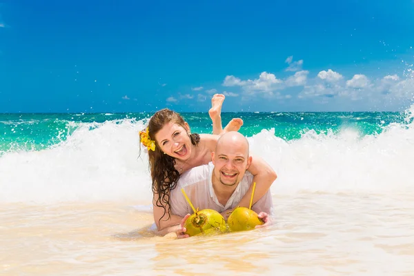 Счастливые жених и невеста веселятся на тропическом пляже. Свадьба — стоковое фото