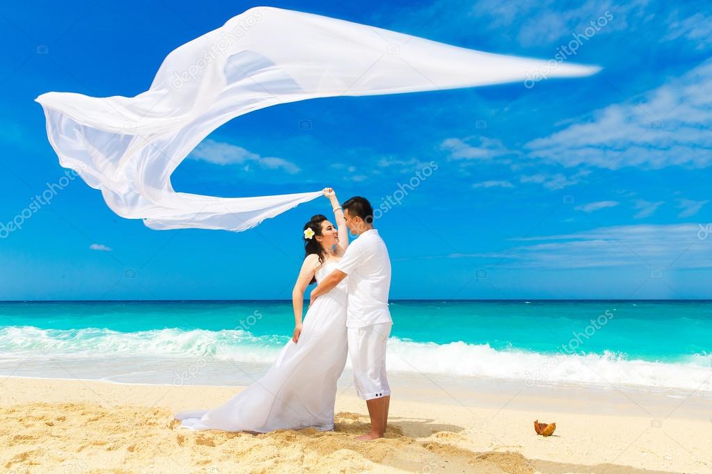 Asian bride and groom on a tropical beach. Wedding and honeymoon