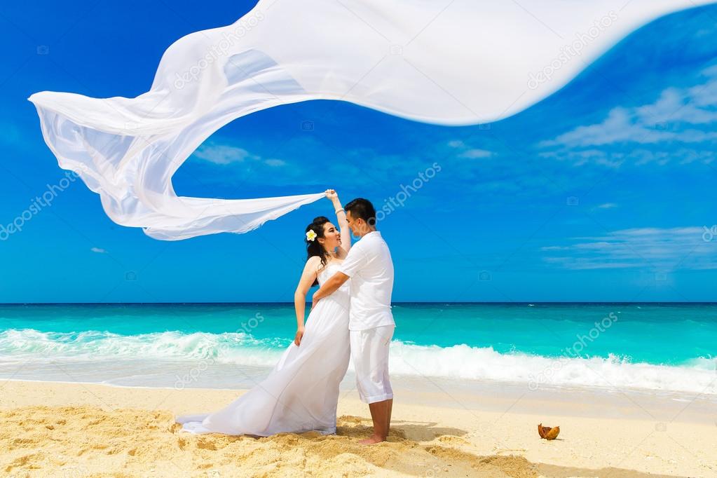 Asian bride and groom on a tropical beach. Wedding and honeymoon
