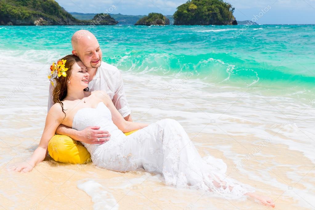 Happy bride and groom having fun on a tropical beach. Wedding an