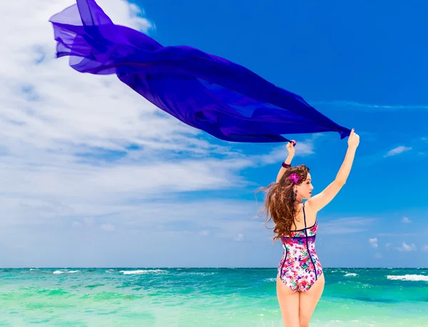 Happy young brunette in a swimsuit dancing with a purple cloth o — Stock Photo, Image