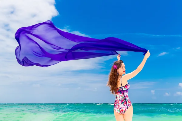 Щаслива молода брюнетка в купальнику танцює з фіолетовою тканиною — стокове фото