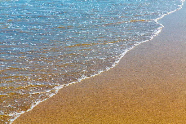Fechar a espuma do mar na areia dourada molhada com espaço de cópia — Fotografia de Stock