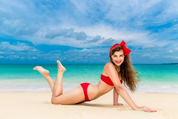 Pin up schöne junge Frau im roten Bikini an einem tropischen Strand. — Stockfoto