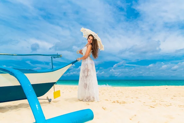 Beautiful young woman in white dress with umbrella on a tropical — Stock fotografie