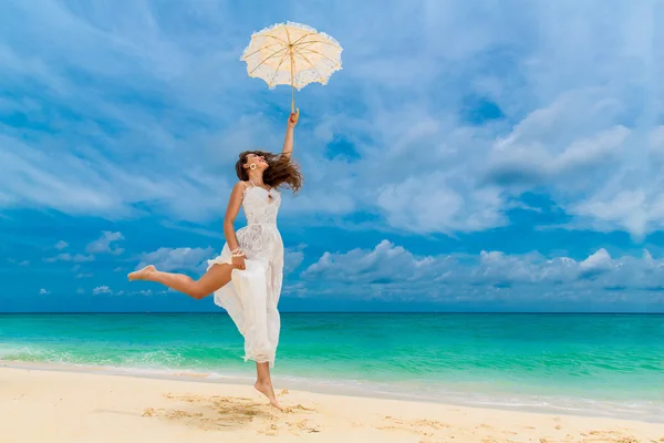Beautiful young woman in white dress with umbrella on a tropical — Stok fotoğraf